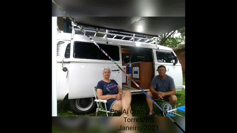 Eduardo e Niaia sentados junto à Kombi aberta, em Torres RS